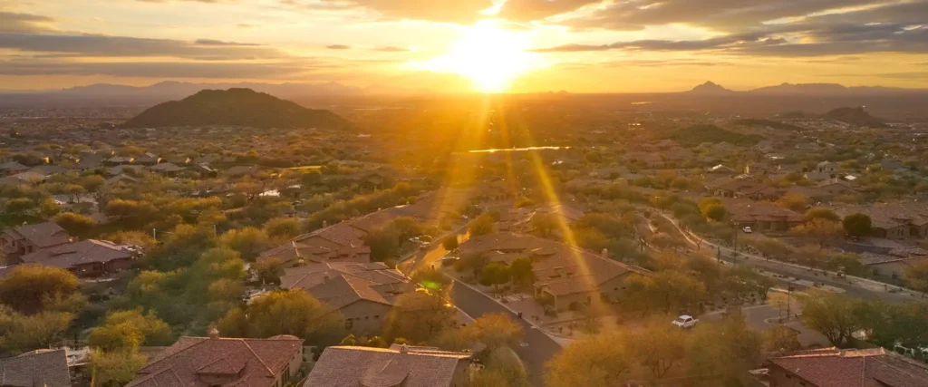 Aerial view of a residential neighborhood at sunset with desert hills and mountain views