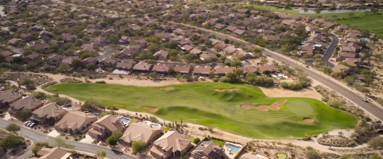 Aerial view of Arizona residential homes surrounding a green golf course in a desert neighborhood